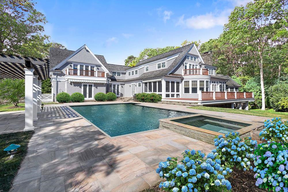 Khu vực spa với hồ bơi và bồn tắm nước nóng ngoài trời ở sân sau được bao quanh bởi vườn cây hoa lá, cỏ cây tốt tươi.