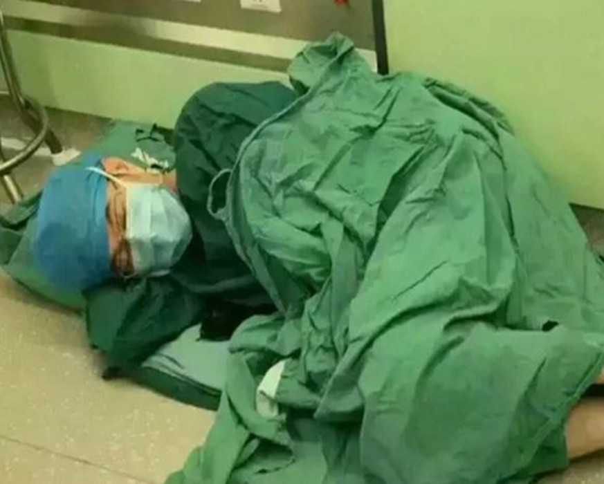 Đây là hình ảnh một vị bác sĩ trong một ngày hoàn thành 18 ca phẫu thuật, anh ấy đã quá mệt, và nằm ngủ ở một góc của phòng phẫu thuật.