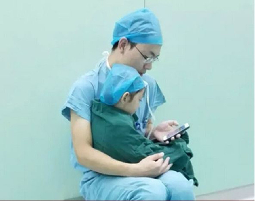Trong hình là bé gái sắp bước vào ca phẫu thuật tim, cô bé khóc không ngừng, để khiến cô bé ngừng khóc, bác sĩ đã cùng bệnh nhân nhí xem điện thoại di động.