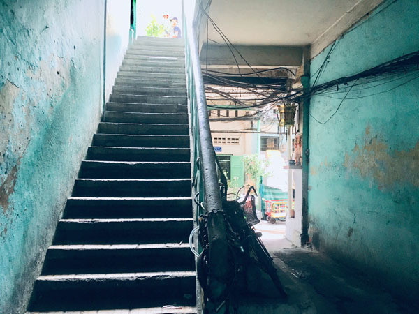 Đi qua quán cà phê cóc đầu hẻm là cầu thang lên xuống làm bằng sắt, nhỏ hẹp, tối tăm. Ảnh: T.A.
