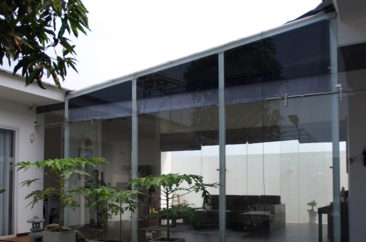 Một phần kính của mái được gập xuống tạo thành bức tường ngăn cách phòng khách và sân trong, tạo sự riêng tư mà vẫn đảm bảo lấy ánh sáng.
