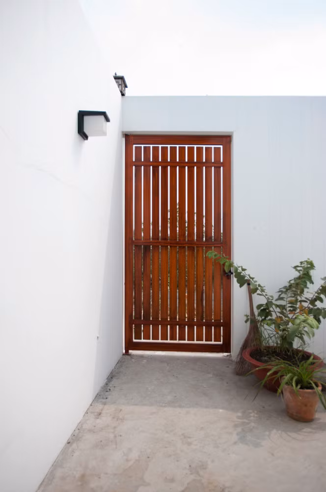 Sau cánh cổng là khoảng sân, khu vườn, có ao cá và cây xanh.