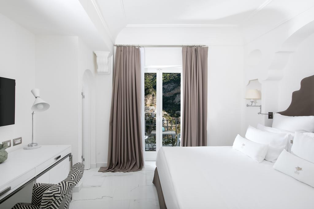 Các phòng nghỉ trong khách sạn sử dụng toàn bộ gam màu trắng, có ban công hướng ra thị trấn. Ảnh: Booking.