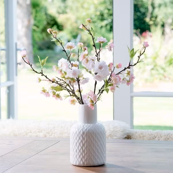 Cành đào trên bàn trà cạnh khung cửa sổ giúp cho căn nhà nhỏ thêm bình yên và đẹp hài hòa. Ảnh: Em đẹp.