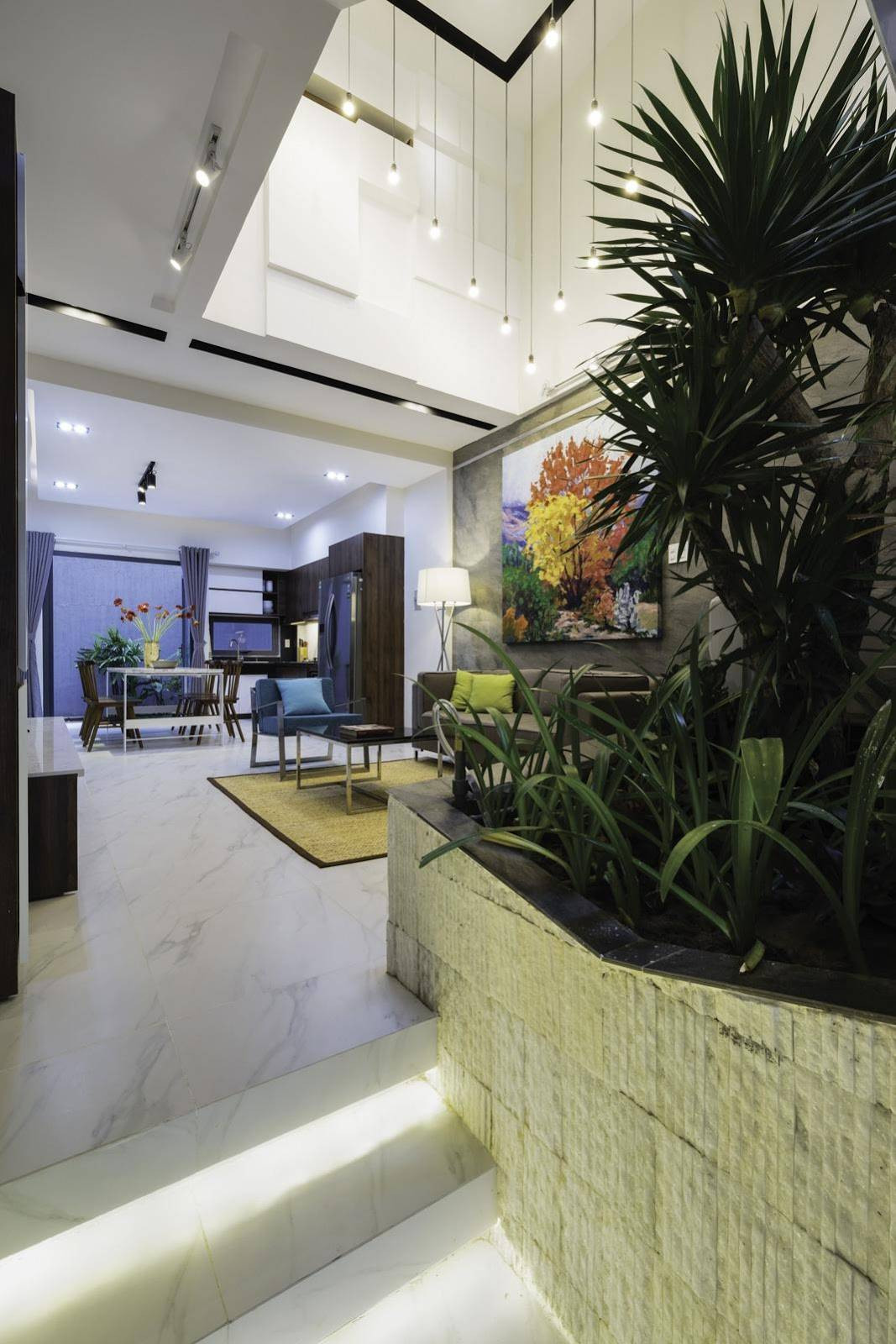 Không gian phía ngoài của tầng 1 làm gara, phía trong giật cấp thành không gian phòng khách, khu vực bếp và bàn ăn.