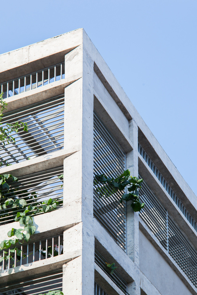 Tường bao quanh nhà là những mảng bê tông xen lẫn hệ lam sắt, có tác dụng đón nắng và gió trời.