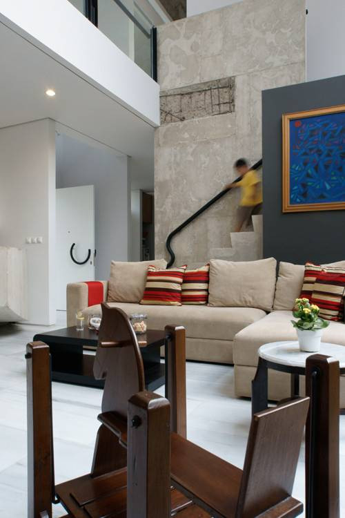 Ngoài 3 phòng ngủ khép kín, các không gian khác trong ngôi nhà 2 tầng đều mở với trần bê tông và bức tường màu trắng xám.