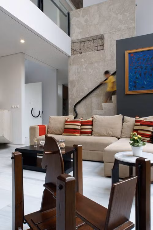 Ngoài 3 phòng ngủ khép kín, các không gian khác trong ngôi nhà 2 tầng đều mở với trần bê tông và bức tường màu trắng xám.