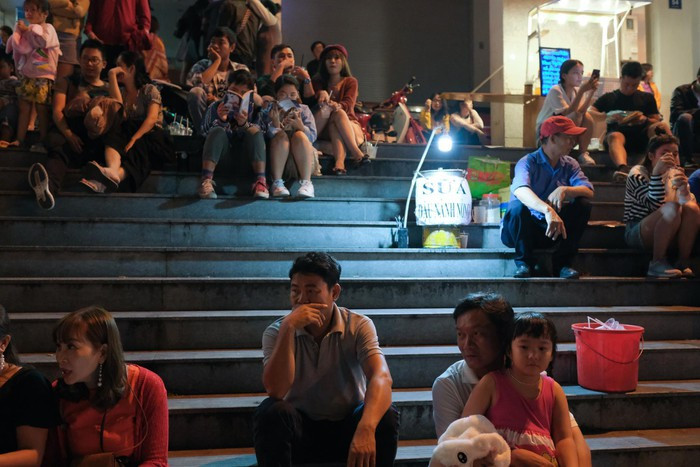 Nhiều người vì mệt, không muốn chen chúc, lựa chọn ngồi trên các bậc thềm trước rạp Hòa Bình.