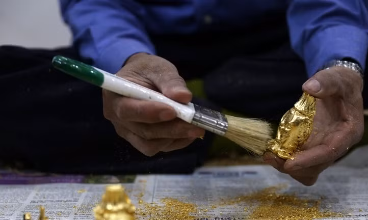 Công đoạn dát vàng trên sản phẩm được thực hiện trong phòng kín gió để tránh lá quỳ mỏng bị thổi bay. Ảnh: Baoanhvietnam.