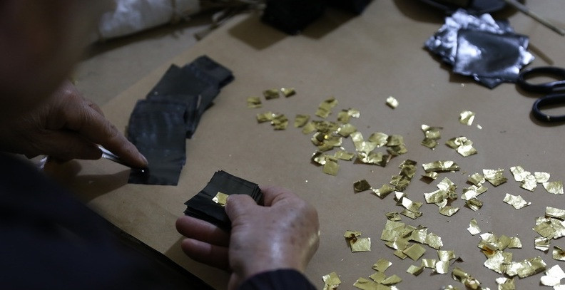 Sau khi long quỳ xong, người thợ lại gói quỳ vào hai mảnh vải và giã tiếp cho vàng thật mỏng. Ảnh: Baoanhvietnam.