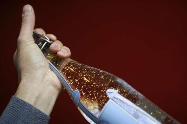 Một người đàn ông cầm chai nước chanh chứa các lá vàng 24 karat. Sản phẩm do công ty Elixia Faustin, Pháp sản xuất năm 2010.