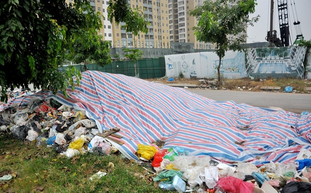 Ban quản lý tòa nhà dùng tấm bạt lớn nhưng chỉ phủ được một phần đống rác thải không di chuyển được do người dân chặn đường vào bãi rác Nam Sơn. Ảnh: Batdongsanvietnam.