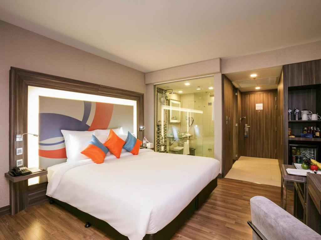 Các phòng nghỉ tại khách sạn được trang trí nội thất gỗ có ghế sofa và tủ lạnh với minibar và TV màn hình phẳng. Ảnh: Agoda.