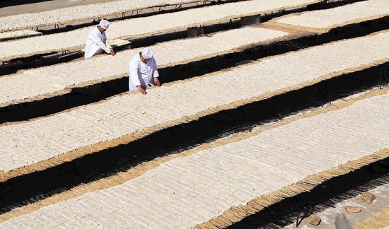 Công nhân kiểm tra đậu phụ đang được phơi khô trên sân, tại tỉnh Hà Bắc, Trung Quốc. Ảnh: Xinhua.