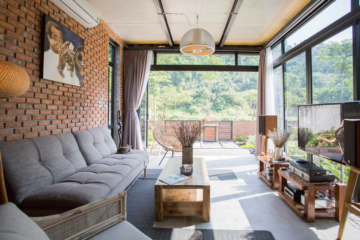 Phòng khách ấn tượng với tường gạch trần, cửa kính lớn.