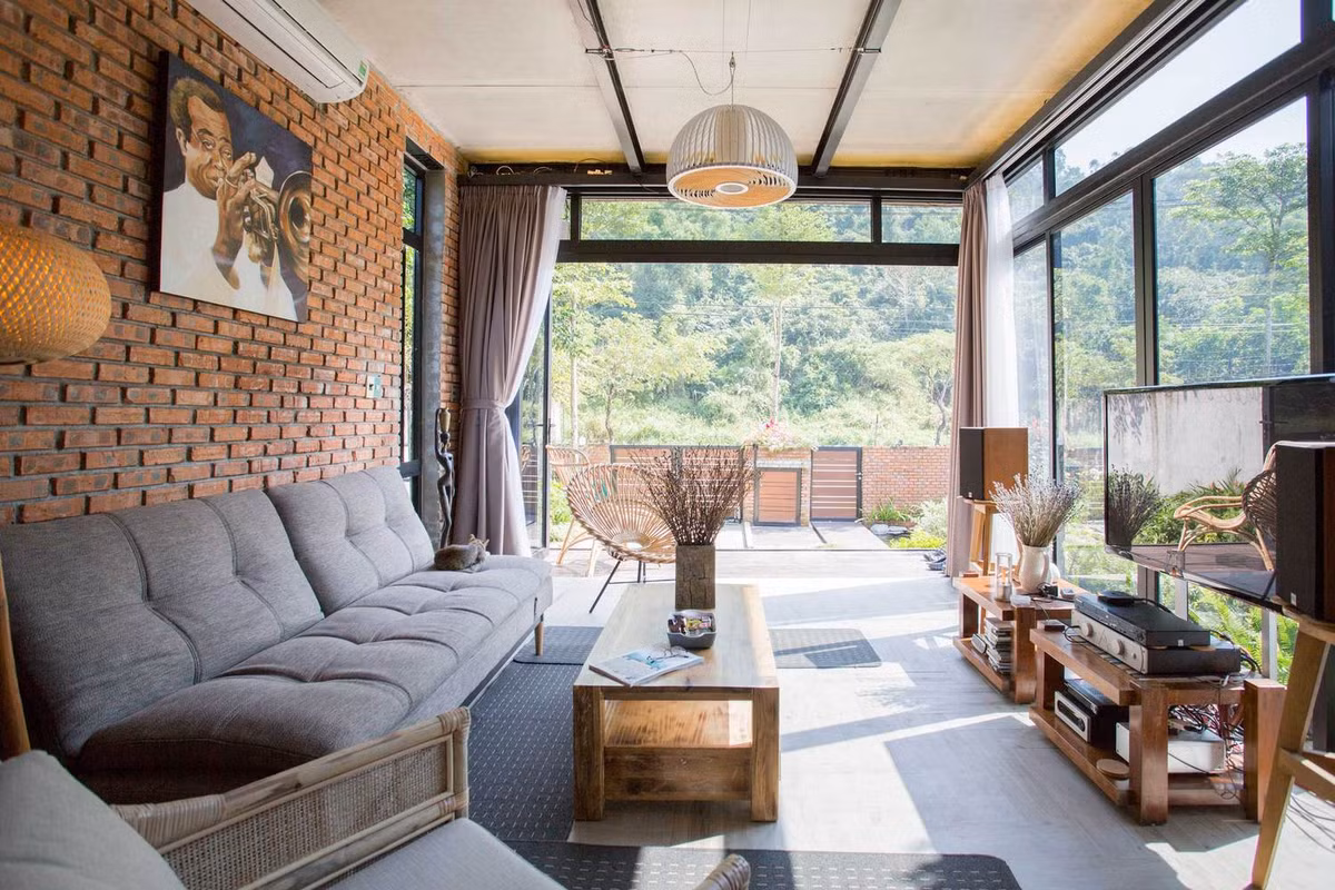 Phòng khách ấn tượng với tường gạch trần, cửa kính lớn.