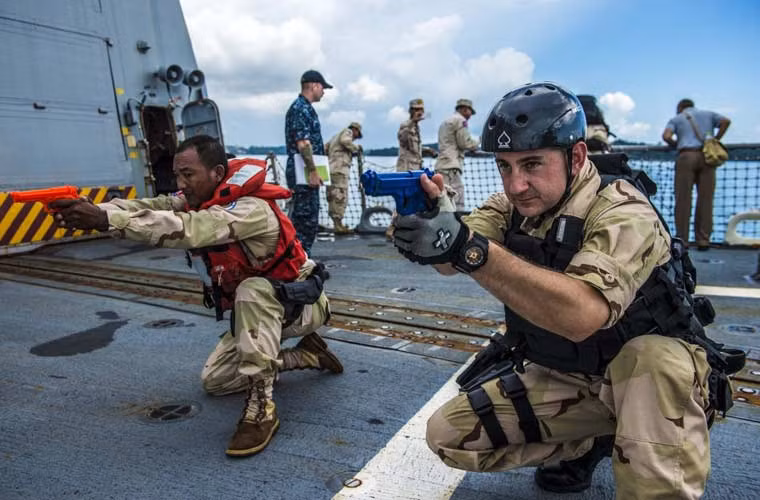 Một người lính Campuchia (trái) đang huấn luyện trên khu trục hạm mang tên lửa dẫn đường USS Mustin (DDG-89) của Hải quân Mỹ.