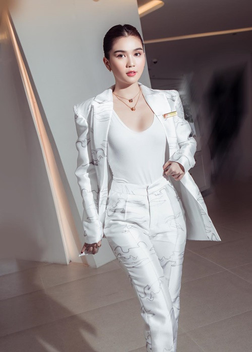 Cô diện vest màu trắng, búi tóc cao.