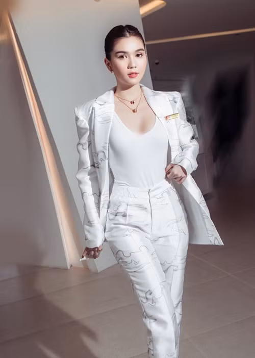 Cô diện vest màu trắng, búi tóc cao.