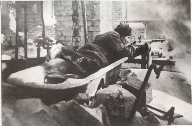 Tất cả mọi thứ gồm cả vật dụng sinh hoạt được tận dụng trở thành những công sự chiến đấu. Trong ảnh, chiến sĩ Hồng quân nằm bắn tiểu liên trên một chiếc bồn tắm. Nguồn ảnh: WHO