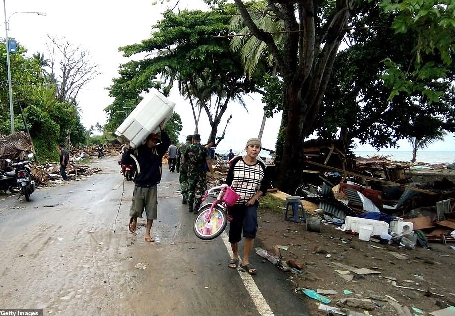 Người dân địa phương dọn đồ khỏi những ngôi nhà bị hư hại trên bãi biển Carita, Baten. Ảnh: Getty.