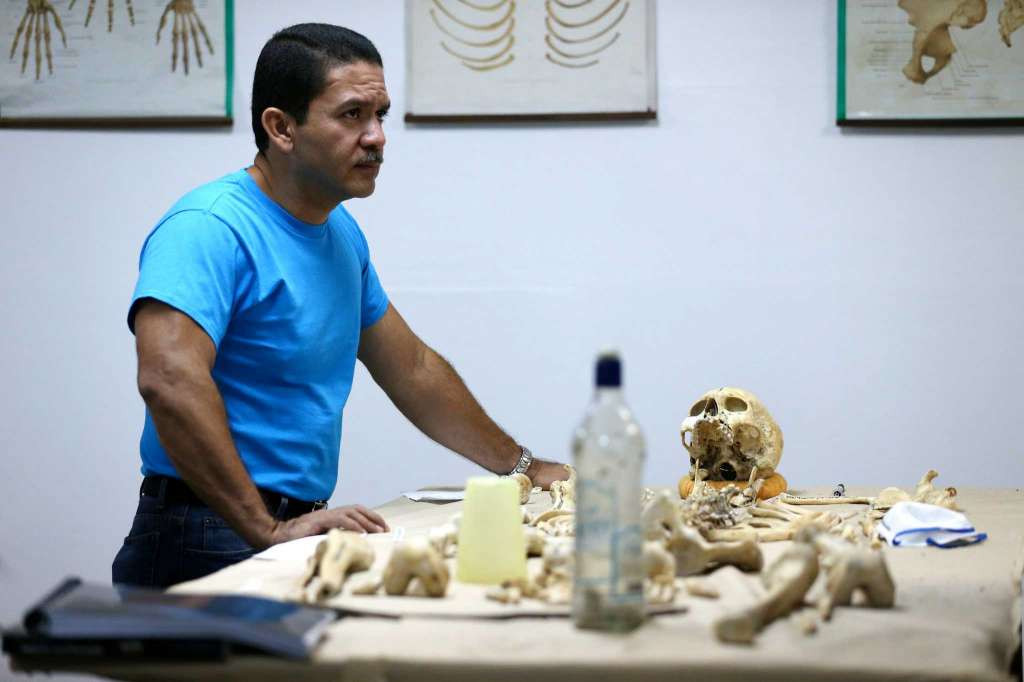 Tiến sĩ Saul Quijada, 47 tuổi, chuyên gia pháp y tại Viện Y học Pháp lý El Salvador bên cạnh bộ xương của một nam giới tử vong trong vụ bạo lực ở San Salvador ngày 4/4/2016.