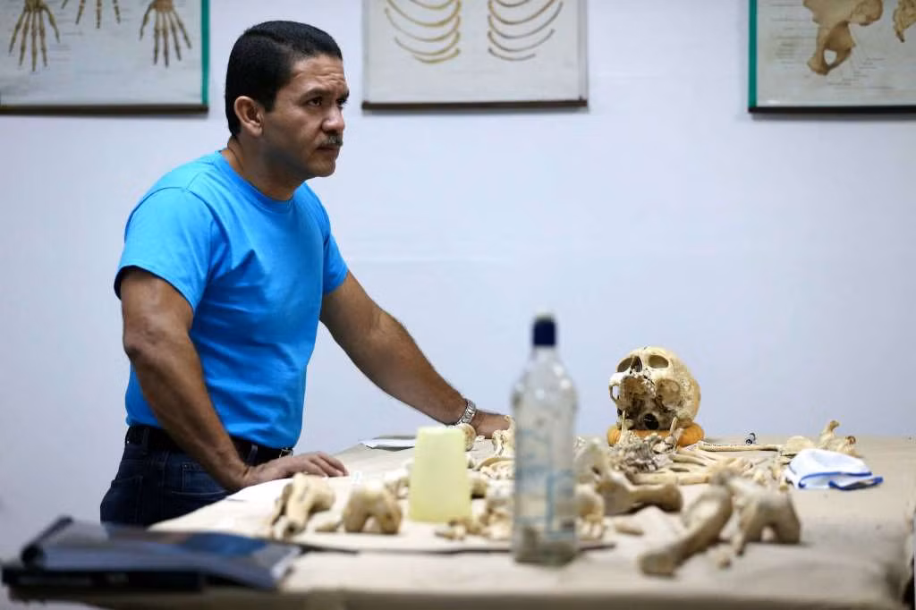 Tiến sĩ Saul Quijada, 47 tuổi, chuyên gia pháp y tại Viện Y học Pháp lý El Salvador bên cạnh bộ xương của một nam giới tử vong trong vụ bạo lực ở San Salvador ngày 4/4/2016.