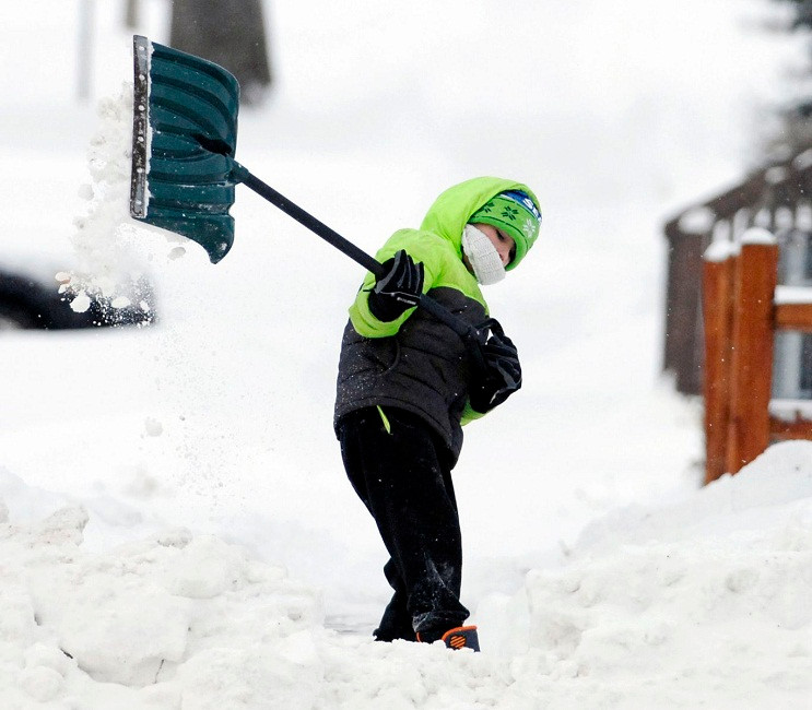 Bé Vincent Schaff, 8 tuổi, dọn tuyết trên vỉa hè nhà bà ngoại cậu bé dọc Đại lộ Rosser ở Bismarck ngày 27/12. Ảnh: AP.