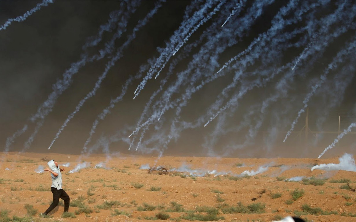 Một người biểu tình Palestine đứng trong làn khói hơi cay mù mịt.