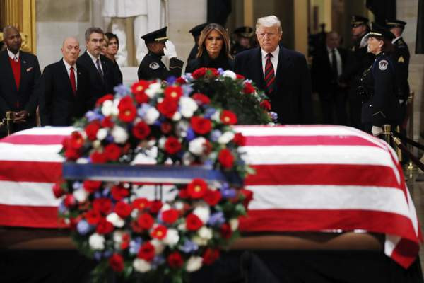 Tổng thống Trump và phu nhân Melania đứng cạnh linh cữu cố Tổng thống Bush "cha" trong buổi lễ tưởng niệm. Ảnh: AP.