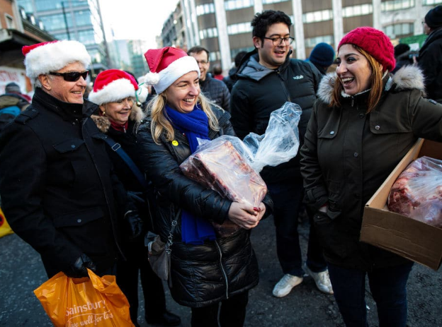 Mọi người cầm những túi thịt vừa mua tại buổi bán đấu giá thịt Harts được tổ chức thường niên dịp lễ Giáng sinh tại khu chợ Smithfield ngày 24/12. Ảnh: Getty.