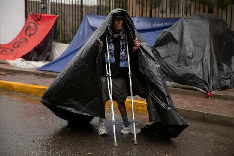 Rafael, 33 tuổi, chống nạng đi dưới cơn mưa nặng hạt ở Tijuana.