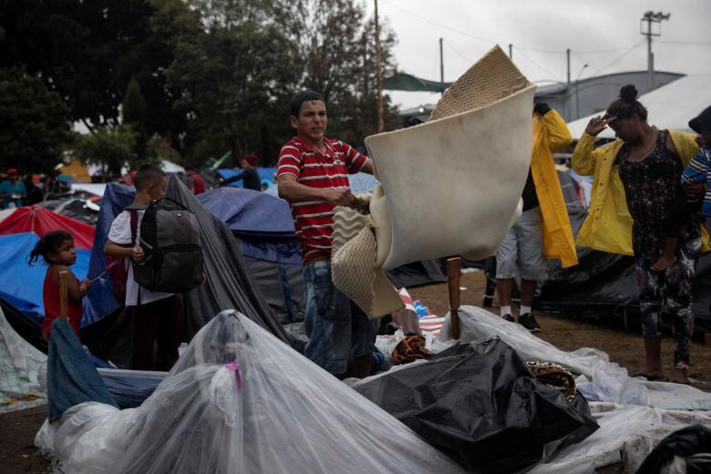 Cuộc sống của những di dân "mắc kẹt" ở biên giới Mỹ-Mexico càng trở nên khốn khổ hơn sau trận mưa lớn ở Tijuana. Ảnh: Một di dân mang đồ đạc ra phơi khô.