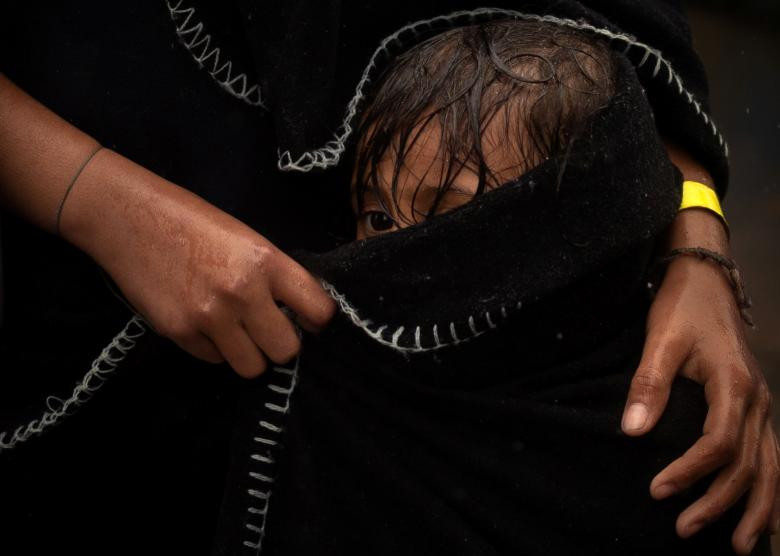 Bé Bassinet, 3 tuổi, đứng cạnh chị gái Rachel, 9 tuổi, dưới trời mưa ở Tijuana.