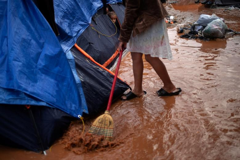 Một bé gái quét nước mưa trong khu trại tị nạn ở Tijuana.