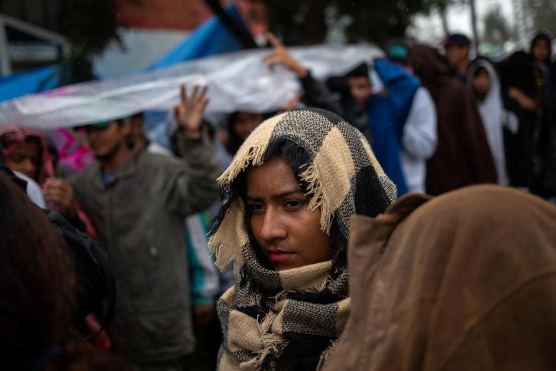 Những người nhập cư xếp hàng nhận đồ ăn được phân phát miễn phí trong khu trú ẩn ở thành phố Tijuana.