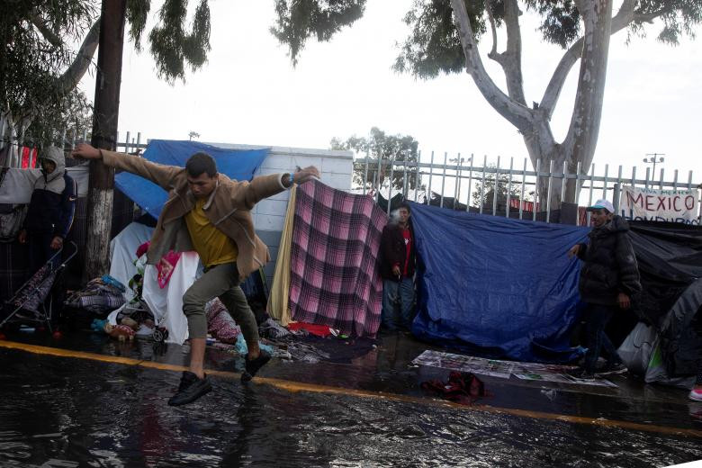 Người đàn ông nhảy qua vũng nước sau khi đem đồ đi phơi ở Tijuana.