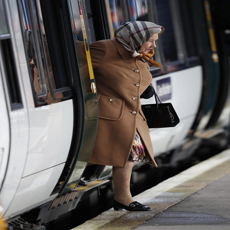 Nữ hoàng Anh Elizabeth II mặc áo khoác màu nâu, choàng khăn bước xuống tàu. Ảnh: The Sun.