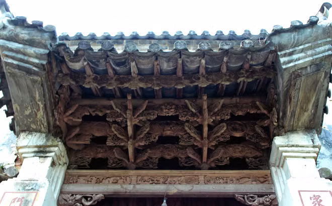 Cổng nhà cong, uốn lượn với những cánh dơi - biểu tượng cho chữ "phúc". Mái cổng bằng gỗ được trạm khắc tinh xảo, với nhiều kiểu hoa văn. Trải qua gần 100 năm, những chi tiết được đục đẽo thanh mảnh vẫn chưa hề mục nát.