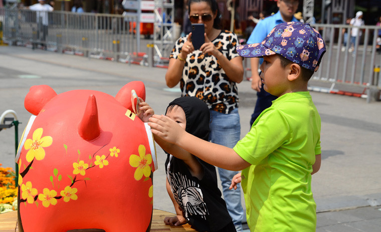 Trẻ em bỏ ống heo tại đường hoa Nguyễn Huệ.