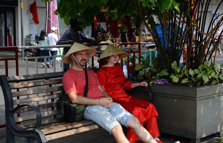 Du khách nước ngoài chống nắng bằng cách riêng của mình khi tham quan đường hoa Nguyễn Huệ.