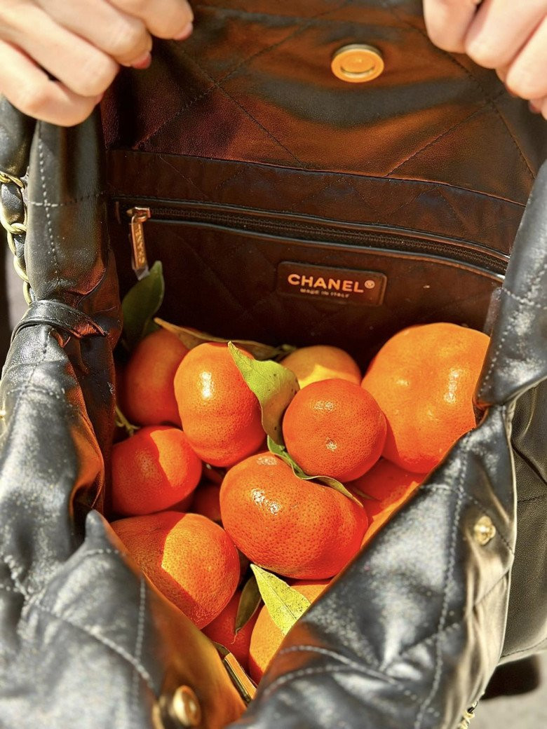 Vợ doanh nhân Nguyễn Quốc Vũ dường như chẳng quan tâm đến chiếc túi mà chỉ hào hứng khoe thành quả đi hái cam của mình.