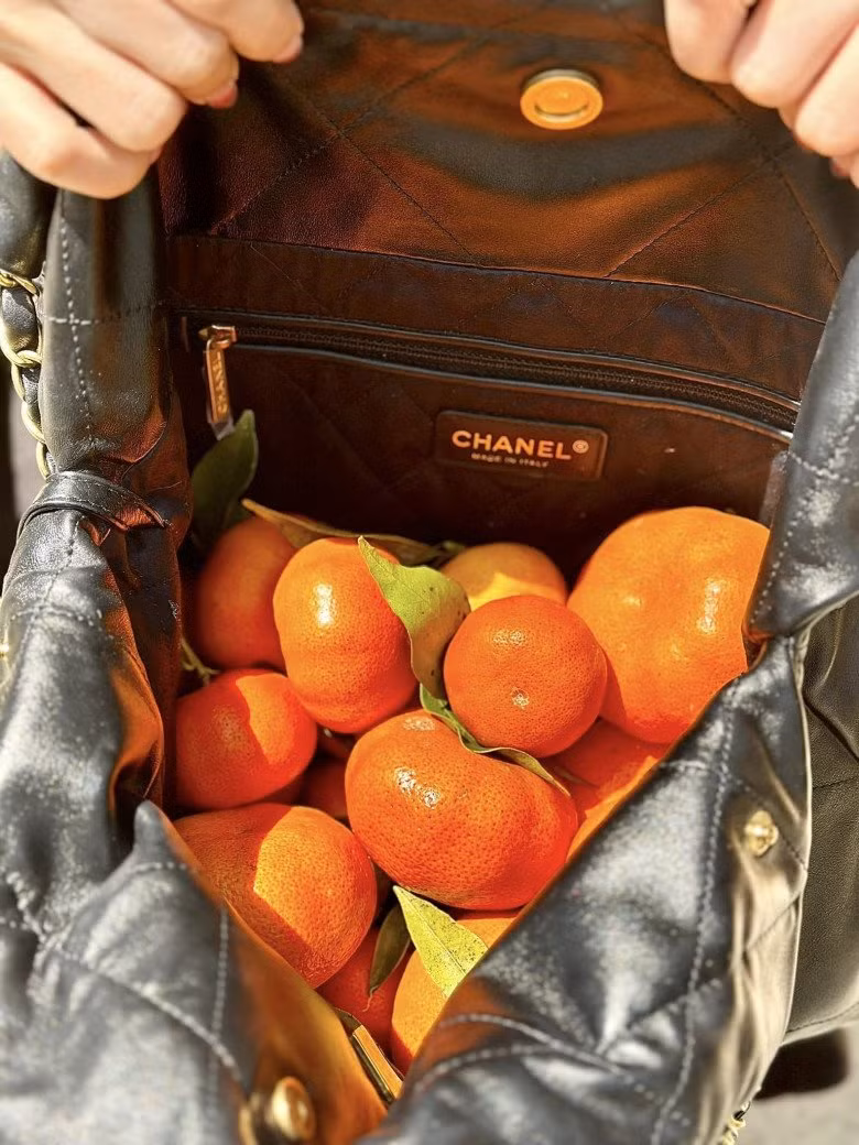 Vợ doanh nhân Nguyễn Quốc Vũ dường như chẳng quan tâm đến chiếc túi mà chỉ hào hứng khoe thành quả đi hái cam của mình.