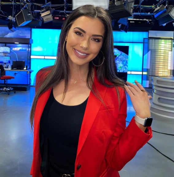 Trong bức hình, nữ phóng viên thể thao diện chiếc áo cổ lọ màu tím, tạo dáng trước trụ sở đội New Orleans Saints.