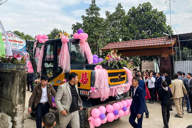 Theo đó, chú rể trong bộ vest lịch thiệp điều khiển máy xúc được trang trí bằng khăn voan, hoa tươi và bóng bay màu hồng đến nhà gái để rước cô dâu về dinh trong đám cưới của mình. Ảnh: Nghệ An