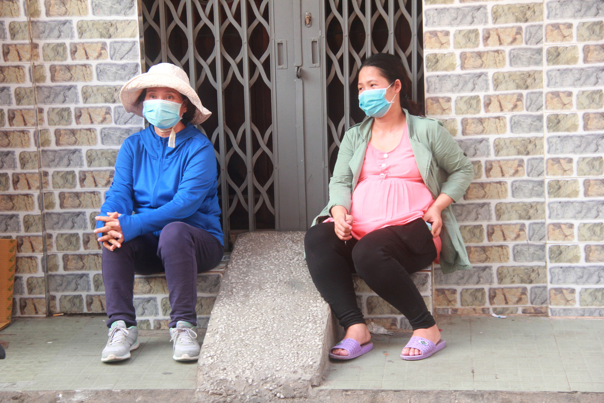 Một bà bầu ngồi trên vỉa hè chờ mua khẩu trang.