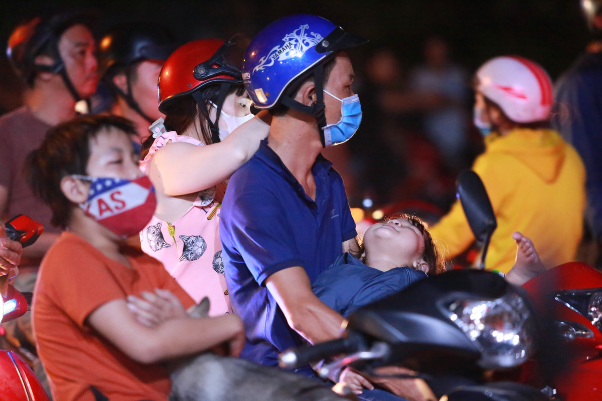 Một em bé ngủ trên tay bố sau nhiều giờ đứng xem bên ngoài hiện trường.