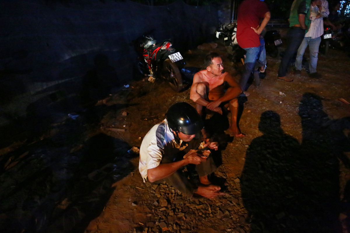 Một người đàn ông trong lúc chờ đợi ăn vội một ổ mì được bán ngay cạnh đó.