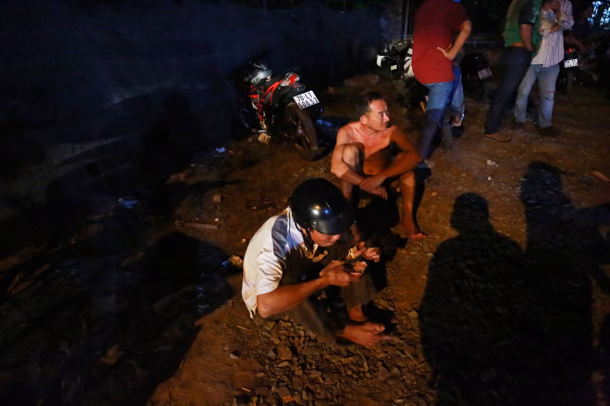 Một người đàn ông trong lúc chờ đợi ăn vội một ổ mì được bán ngay cạnh đó.